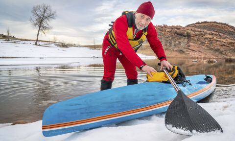 Senior male paddler in drysuit and a racing stand up paddle board on lake in Colorado. | Photo Courtesy: Shutterstock