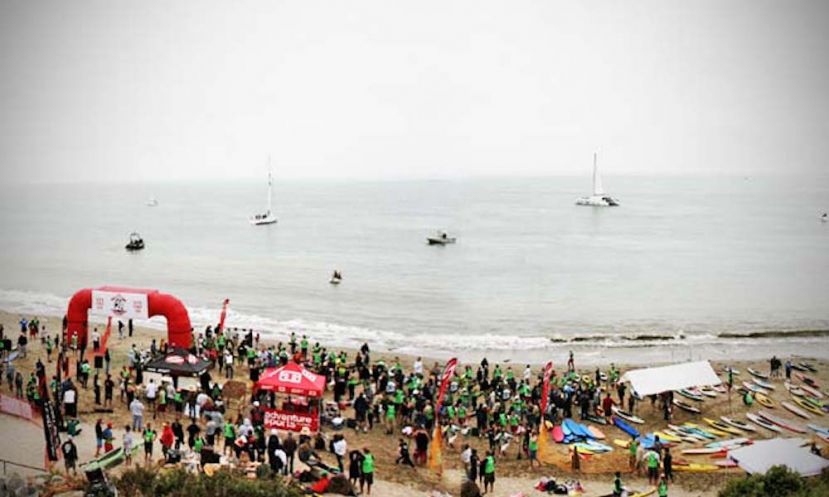 Prone paddleboarders and stand up paddlers stand at the water&#039;s edge at the scene of the Jay Race 2010.