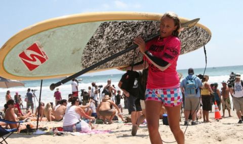 Lisa Anderson toting her stand up paddle board and paddle after some tough sup conditions.