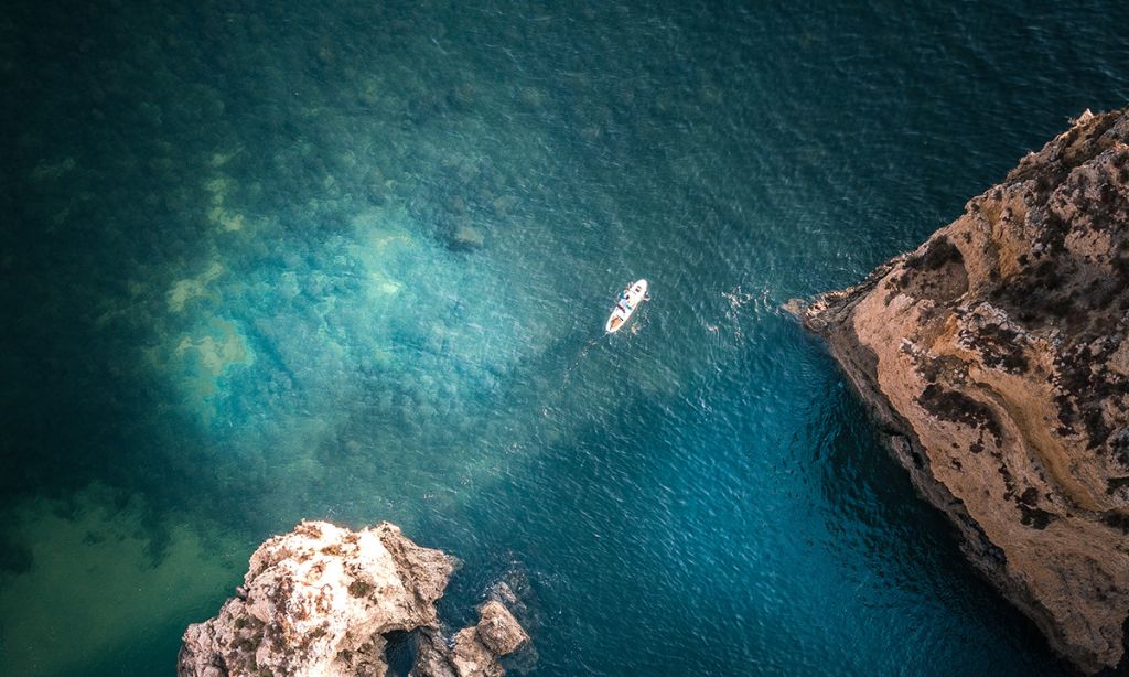 Image of a paddle boarder paddling along the Algarve coast. | Photo: Shutterstock