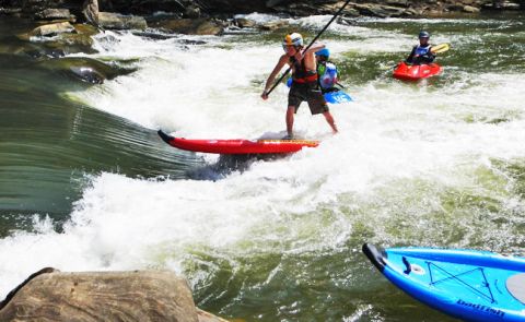 Youth having a swell time in the standing wave at the river in Alabama at the Boardworks Demo Day part of the Inflatable Tour.