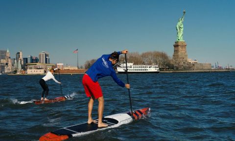 Candice Applebee and unidentified paddler in NYC with the Statue of Liberty in the distance. | Photo: APP / Matt Gunther