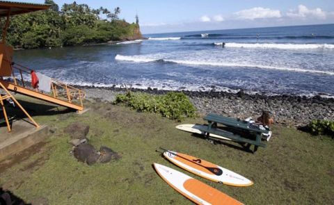 Surf cranking on the outside while stand up paddle boards lie at the water's edge waiting to be put in action.