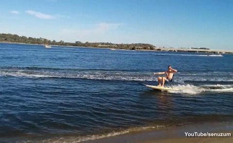 Man Swigs Beer While Being Towed On Paddleboard