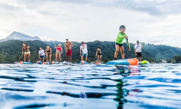 International athletes and local Tahitians paddle together before Air France Paddle Festival. | Photo courtesy: The Paddle League / Georgia Schofield